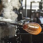 A skilled artisan involved in the intricate process of glass blowing, highlighting craftsmanship.